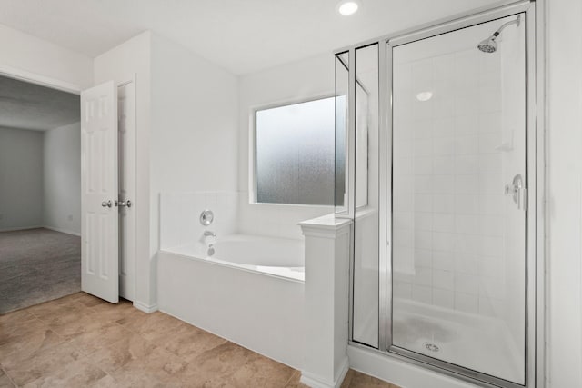 bathroom with a stall shower and a garden tub