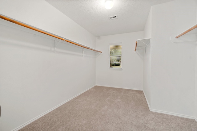 walk in closet with visible vents and light colored carpet