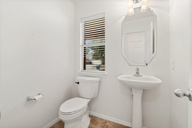 bathroom featuring toilet, baseboards, a sink, and tile patterned floors