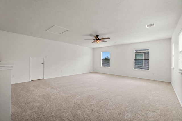 spare room featuring attic access, light colored carpet, visible vents, and a textured ceiling