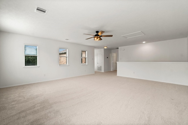 spare room featuring ceiling fan, light carpet, visible vents, baseboards, and attic access