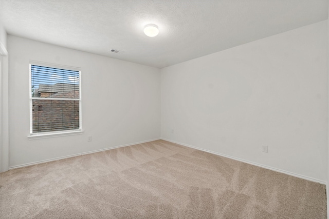 carpeted empty room with visible vents and a textured ceiling