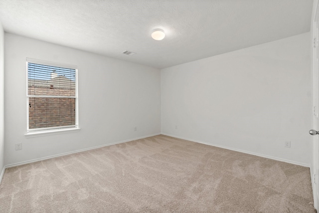 spare room featuring a textured ceiling, carpet flooring, visible vents, and baseboards