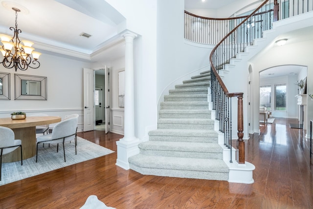 stairs with visible vents, arched walkways, wainscoting, ornamental molding, and wood finished floors