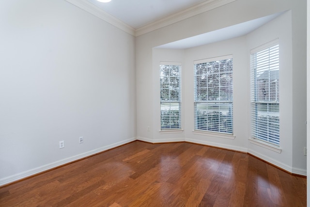 spare room with dark wood-type flooring, ornamental molding, and baseboards