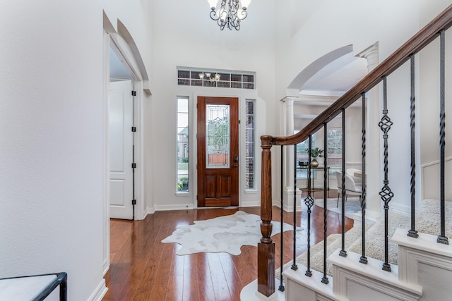 entryway with stairway, a high ceiling, a chandelier, baseboards, and hardwood / wood-style flooring