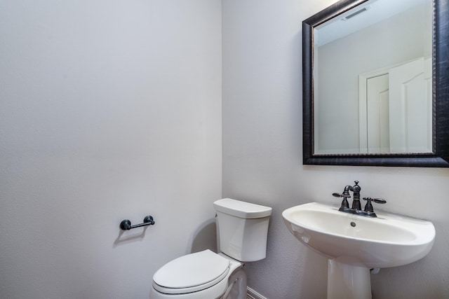 half bath with visible vents, a sink, and toilet