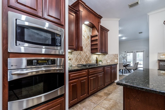 kitchen featuring stainless steel appliances, tasteful backsplash, visible vents, ornamental molding, and dark stone counters