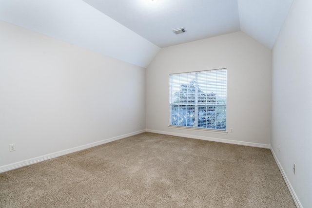 unfurnished room featuring lofted ceiling, carpet floors, baseboards, and visible vents