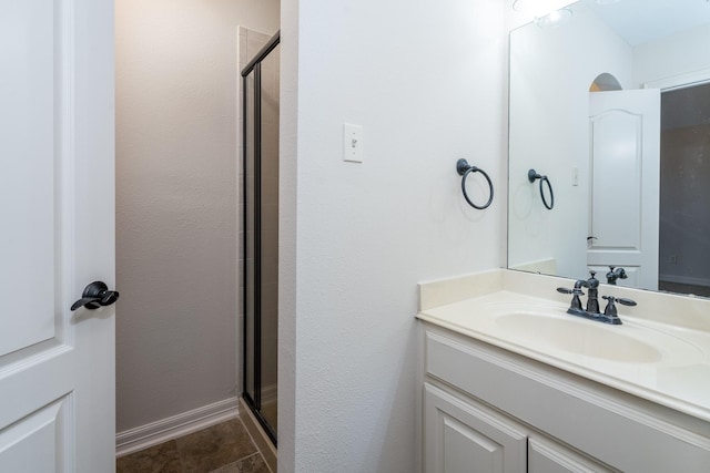 full bath featuring a stall shower, baseboards, and vanity