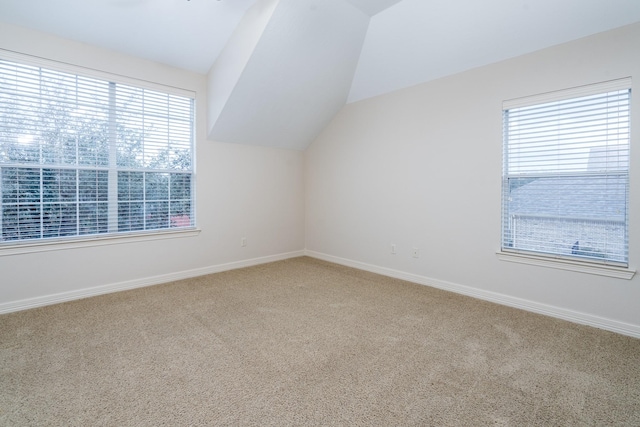 bonus room featuring baseboards, vaulted ceiling, and light colored carpet