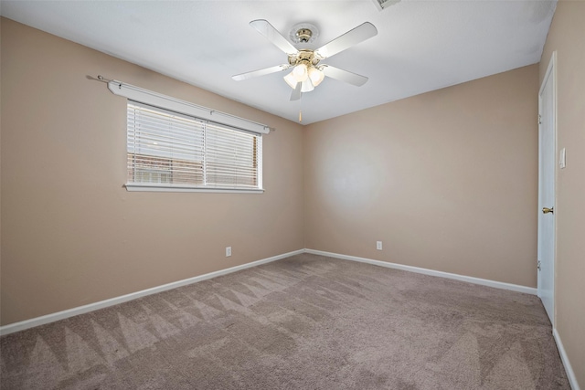 carpeted spare room featuring ceiling fan and baseboards