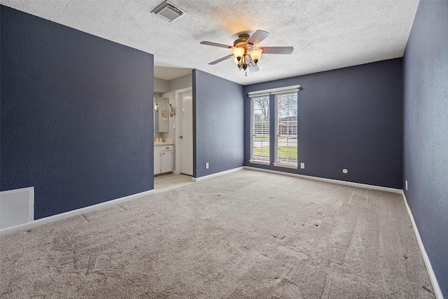 carpeted spare room with a textured ceiling, a textured wall, a ceiling fan, visible vents, and baseboards