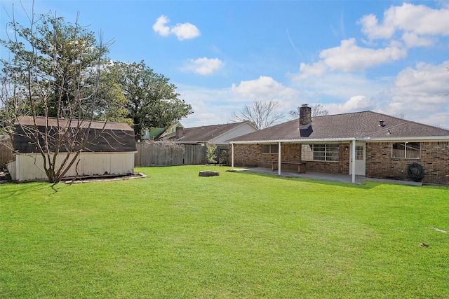 view of yard with a patio area, a fenced backyard, and an outbuilding