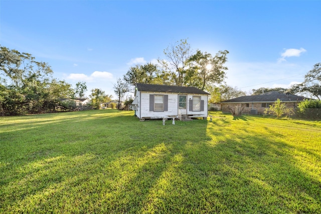 rear view of property featuring an outdoor structure and a yard