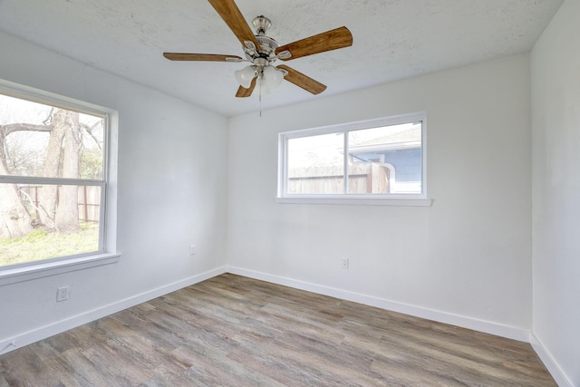 unfurnished room with a textured ceiling, a ceiling fan, baseboards, and wood finished floors