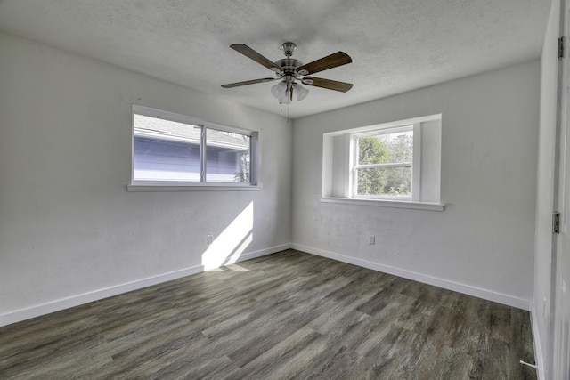 spare room with baseboards, a textured ceiling, and dark wood finished floors