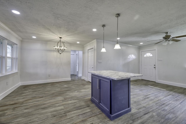 kitchen featuring blue cabinetry, a textured ceiling, dark wood-style floors, a center island, and crown molding