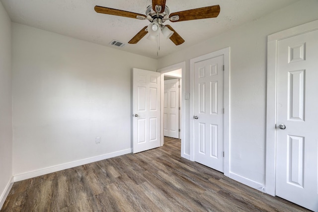 unfurnished bedroom featuring ceiling fan, visible vents, baseboards, and dark wood-style floors