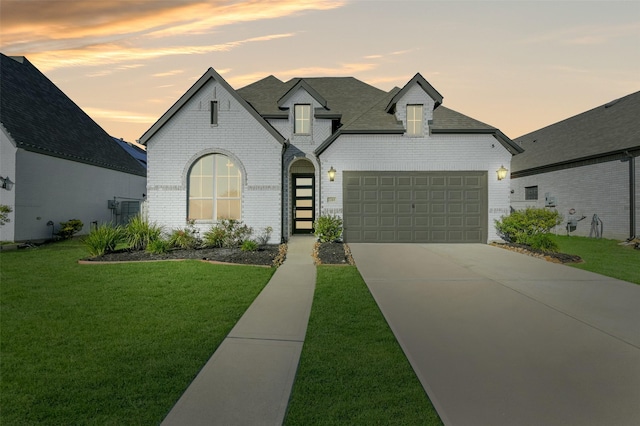 view of front of house featuring an attached garage, brick siding, driveway, roof with shingles, and a front lawn