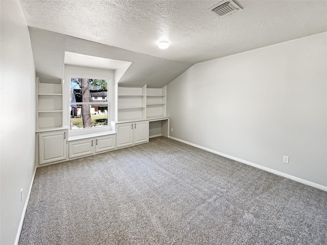 additional living space with light carpet, built in study area, visible vents, and baseboards