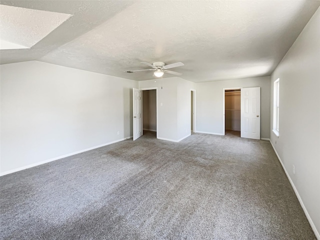 unfurnished bedroom featuring ceiling fan, a textured ceiling, carpet flooring, multiple closets, and baseboards