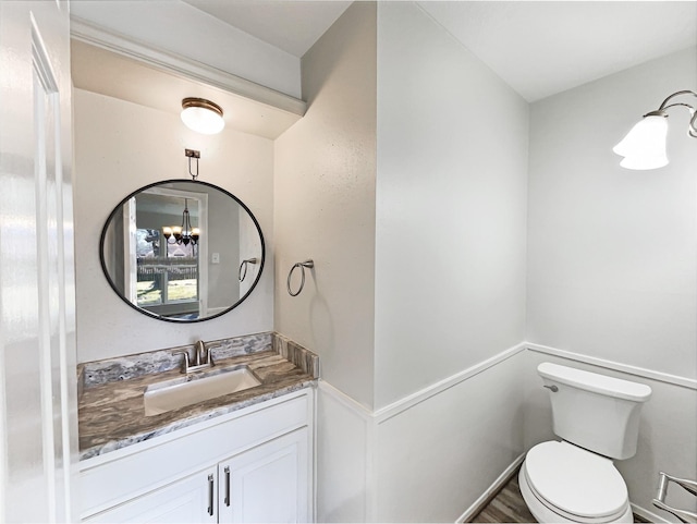 bathroom featuring toilet, an inviting chandelier, and vanity