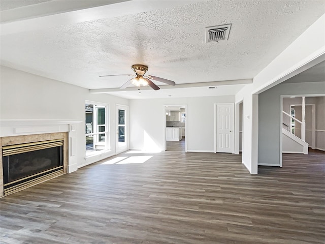 unfurnished living room featuring ceiling fan, a textured ceiling, a fireplace, wood finished floors, and visible vents