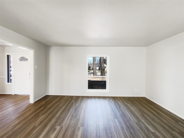 empty room with dark wood finished floors and baseboards