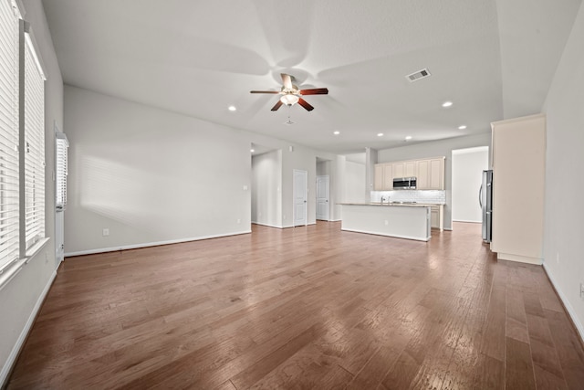 unfurnished living room with recessed lighting, visible vents, a ceiling fan, wood finished floors, and baseboards