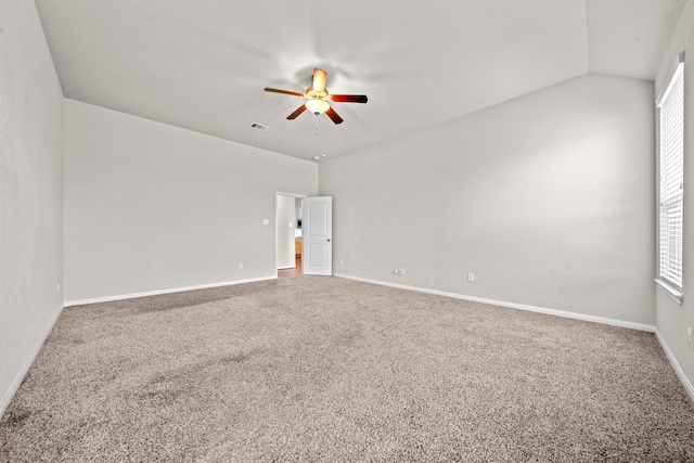 carpeted spare room with lofted ceiling, baseboards, visible vents, and a ceiling fan