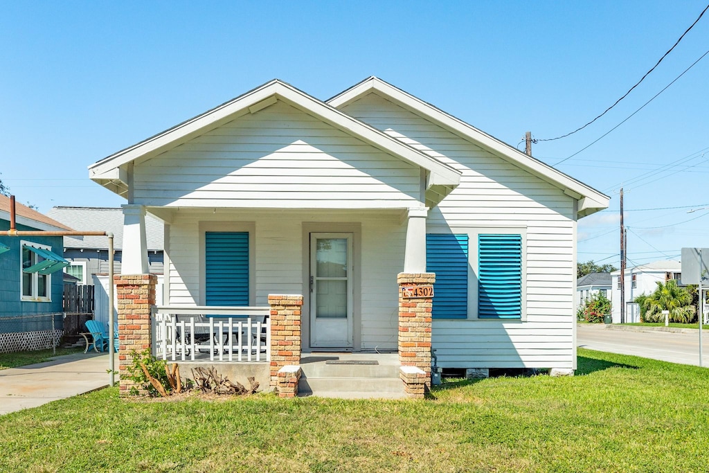 4302 Avenue S 1/2 Ave S 1/2, Galveston, TX 77550 - view of front of home with concrete driveway, a porch, and a front lawn