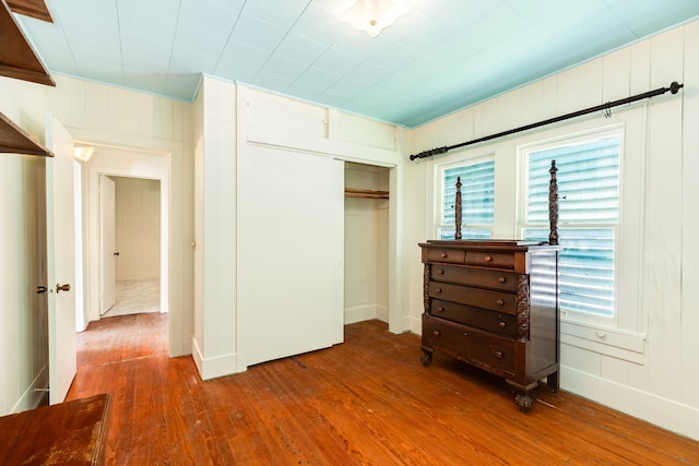 unfurnished bedroom with wood-type flooring, multiple windows, and a closet