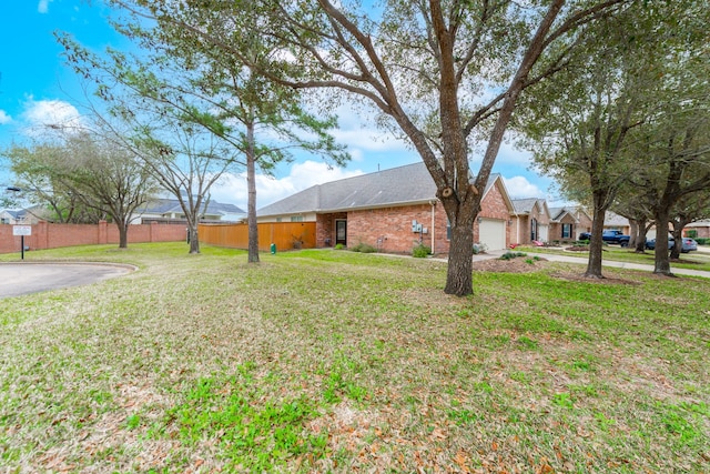 view of yard with an attached garage, fence, and driveway