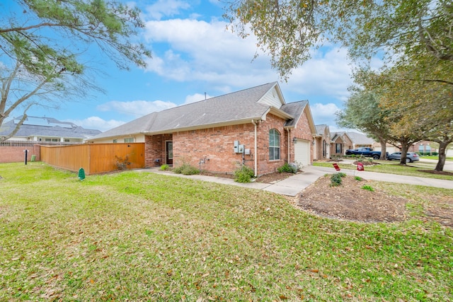 view of side of home featuring fence, a yard, concrete driveway, an attached garage, and brick siding