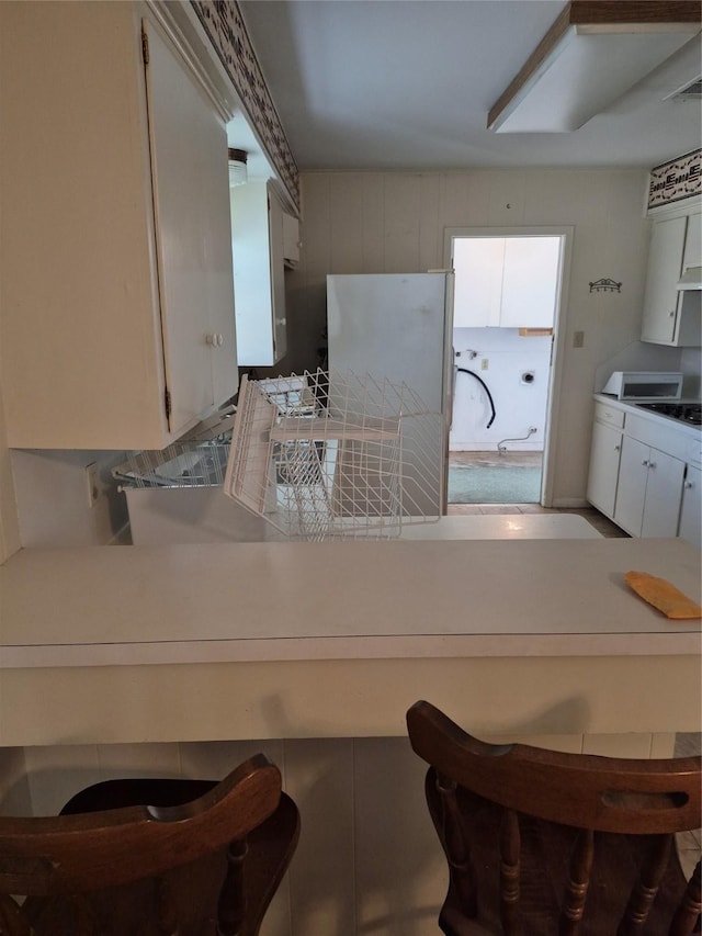 kitchen with a kitchen bar, cooktop, visible vents, and white cabinetry