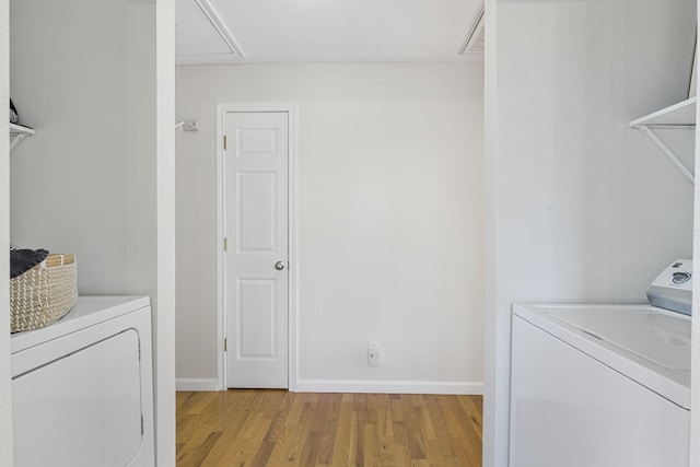 laundry area featuring laundry area, baseboards, separate washer and dryer, and light wood finished floors