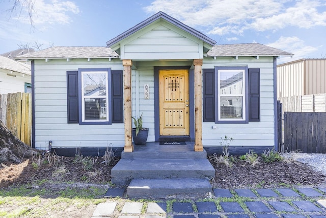 view of front of home featuring a shingled roof and fence