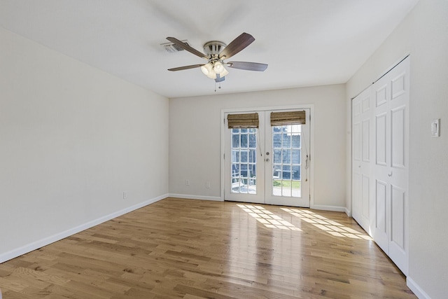 empty room featuring a ceiling fan, baseboards, wood finished floors, and french doors