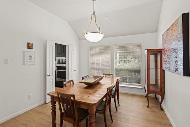 dining space with light wood-type flooring, vaulted ceiling, and baseboards