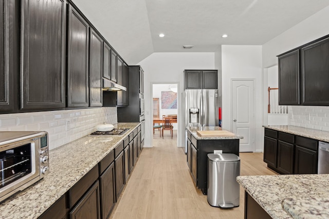 kitchen with stainless steel appliances, light stone counters, light wood-type flooring, and under cabinet range hood