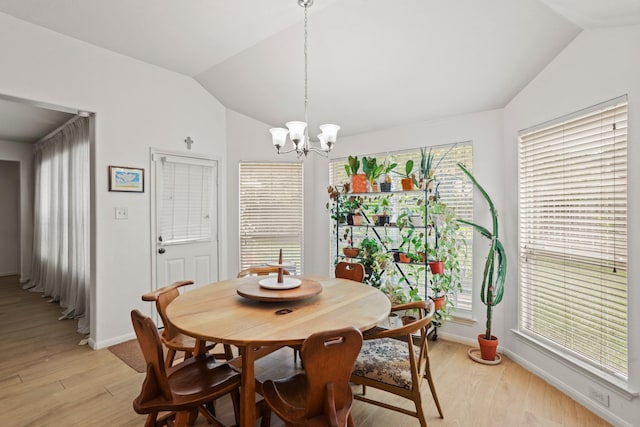 dining area featuring lofted ceiling, light wood-style flooring, baseboards, and a notable chandelier