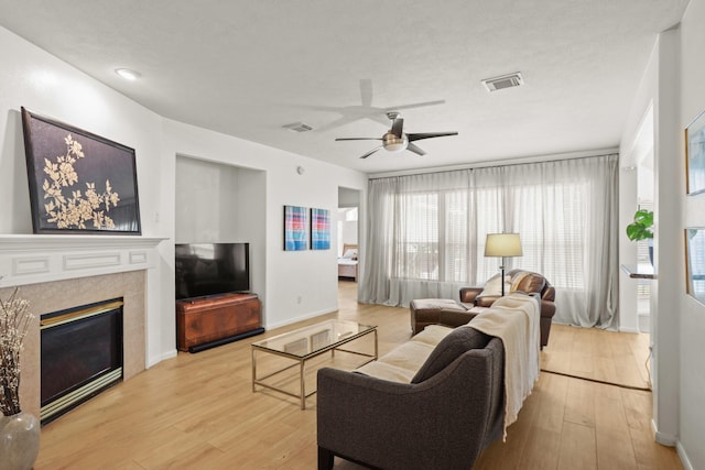 living area featuring light wood-type flooring, visible vents, and a fireplace