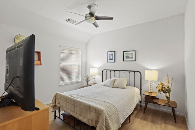 bedroom with lofted ceiling, visible vents, baseboards, and wood finished floors