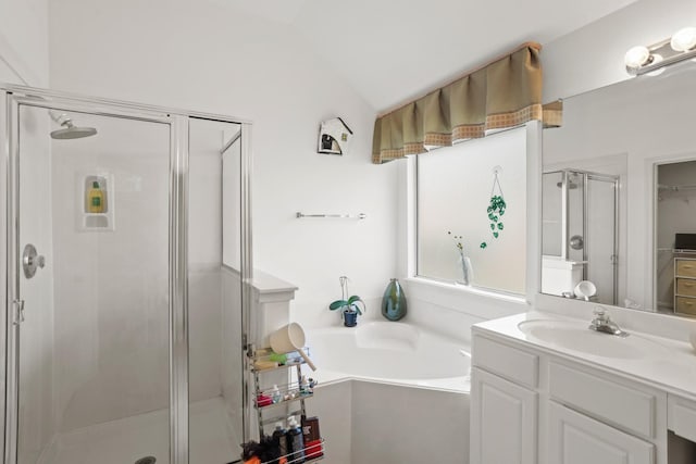 full bath featuring a stall shower, a garden tub, a walk in closet, vaulted ceiling, and vanity