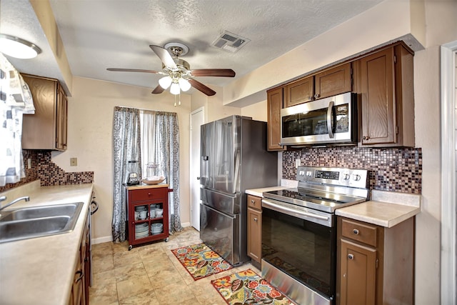 kitchen with visible vents, a sink, stainless steel appliances, light countertops, and backsplash