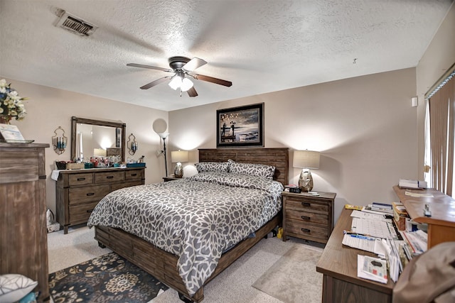 bedroom featuring light colored carpet, visible vents, ceiling fan, and a textured ceiling