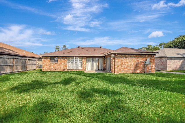 rear view of house with brick siding, fence, and a yard