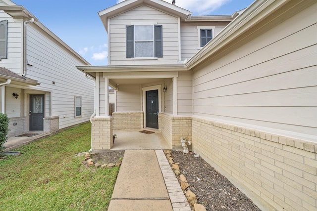 property entrance featuring a porch, brick siding, and a lawn