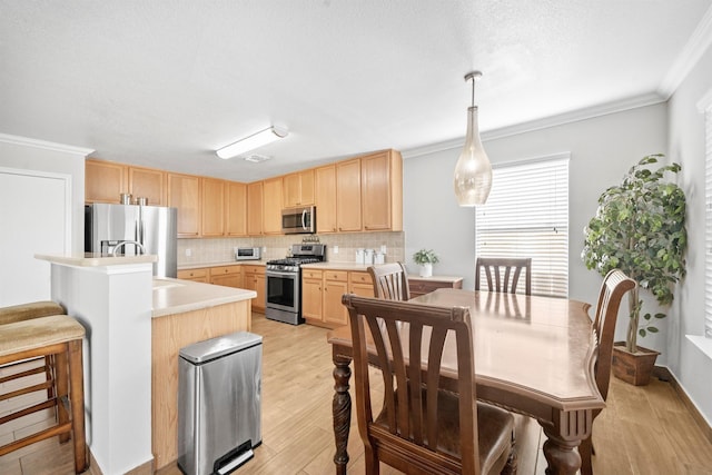 kitchen with decorative backsplash, light wood-style flooring, appliances with stainless steel finishes, light countertops, and light brown cabinets